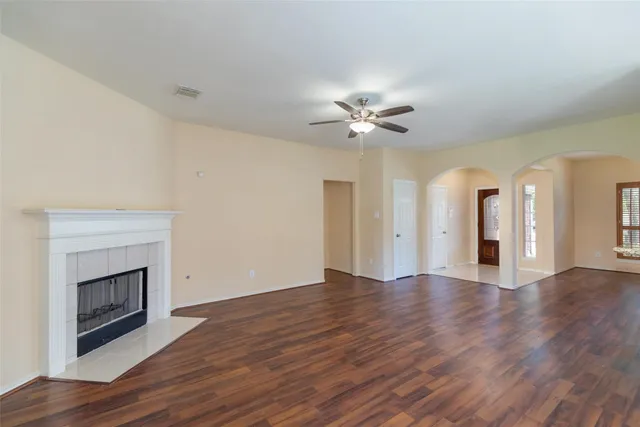 a view of an empty room with wooden floor and a fireplace