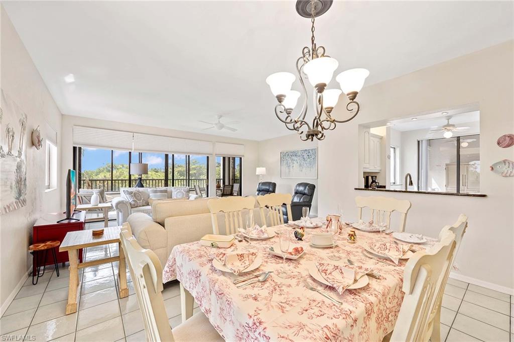 6500 Valen Way, Unit A402 Naples, FL 34108 - Photo 21 of 49 a view of a dining room with furniture wooden floor and a chandelier