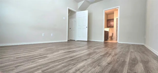 a view of an empty room with wooden floor and closet
