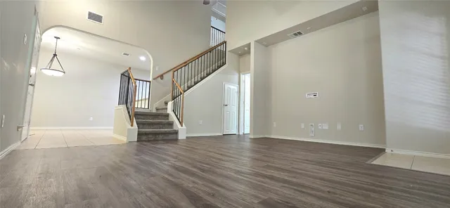 a view of an empty room with wooden floor and stairs
