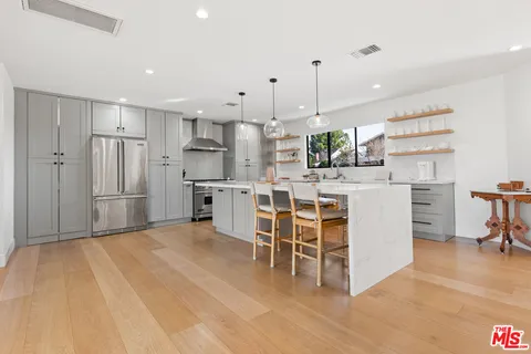 a kitchen with stainless steel appliances kitchen island granite countertop a table chairs refrigerator and microwave