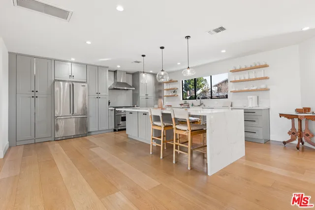 a kitchen with stainless steel appliances kitchen island granite countertop a table chairs refrigerator and microwave