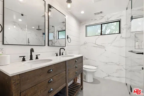a bathroom with a double vanity sink toilet and mirror
