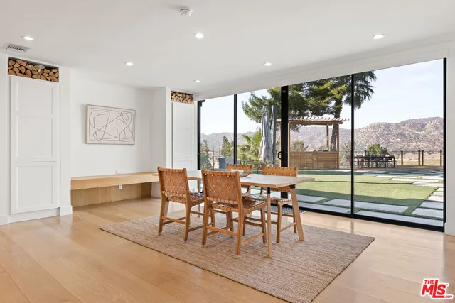 a dining room with wooden floor and a floor to ceiling window