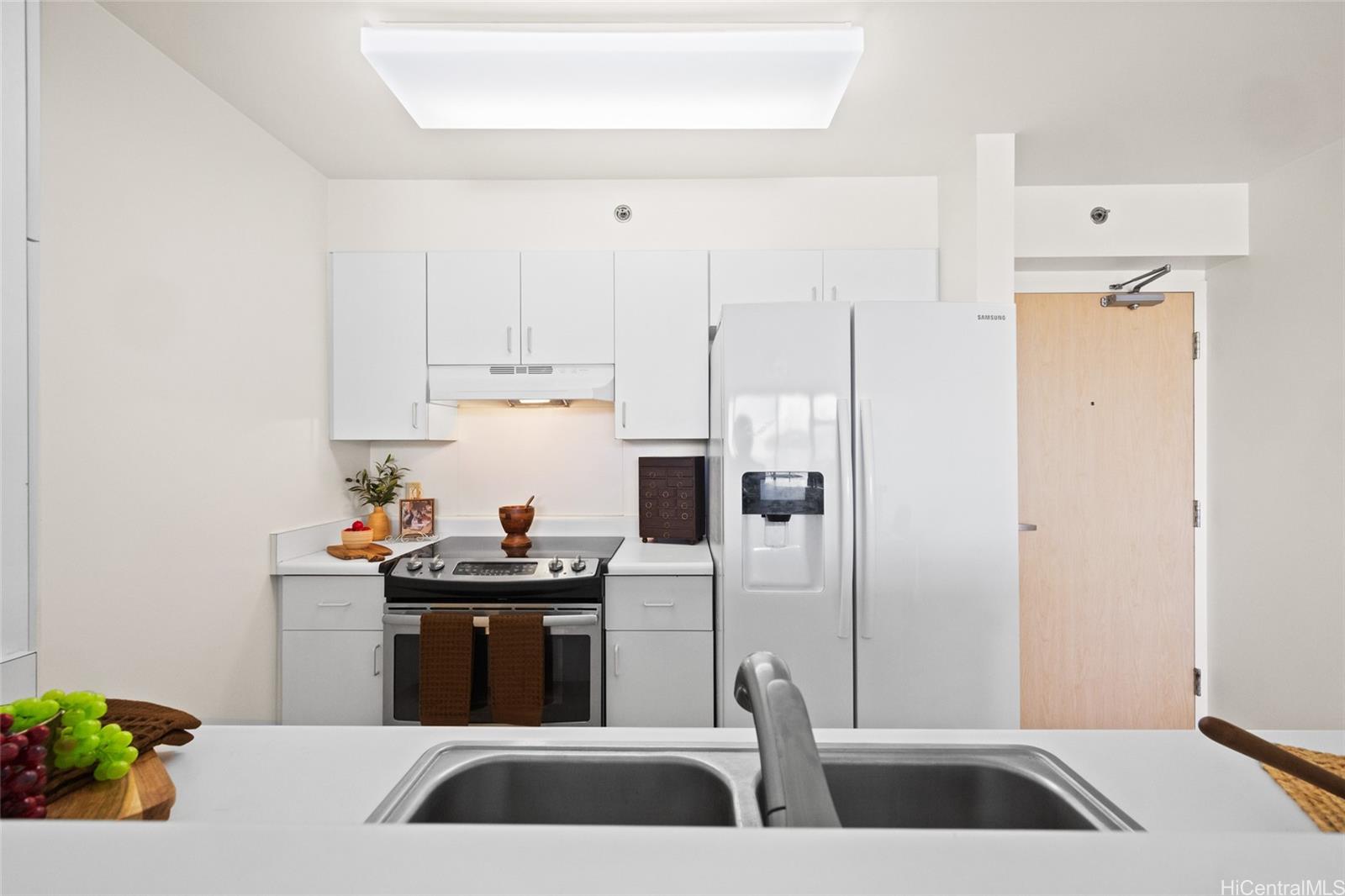 3009 Ala Makahala Place, Unit 1804 Honolulu, HI 96818 - Photo 6 of 20 a kitchen with a sink a refrigerator and cabinets