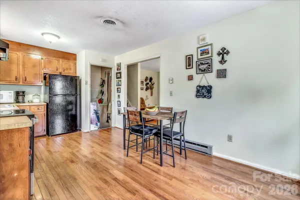 a kitchen with stainless steel appliances granite countertop a refrigerator a stove a dining table and chairs with wooden floor