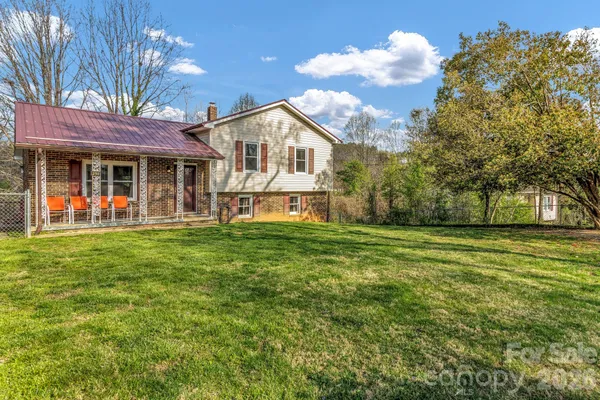 a view of a house with a big yard and large trees