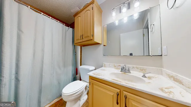 a bathroom with a granite countertop sink vanity mirror and toilet