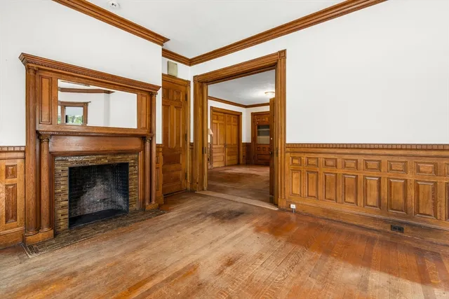 a view of an empty room with wooden floor and a fireplace