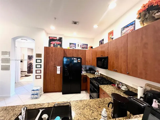 a kitchen with stainless steel appliances kitchen island granite countertop a refrigerator and a stove