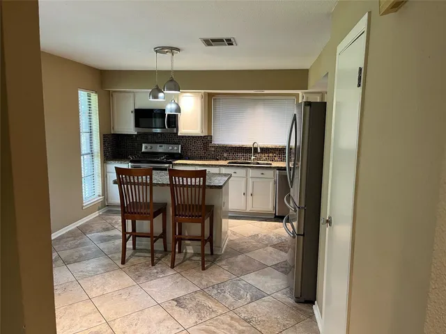 a kitchen with granite countertop a sink cabinets and stainless steel appliances
