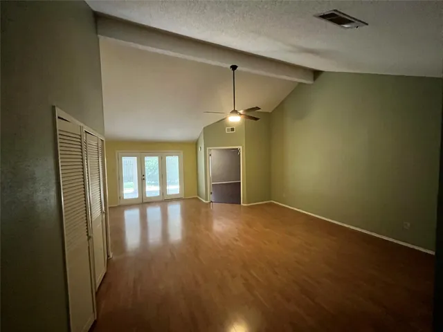 an empty room with wooden floor and windows