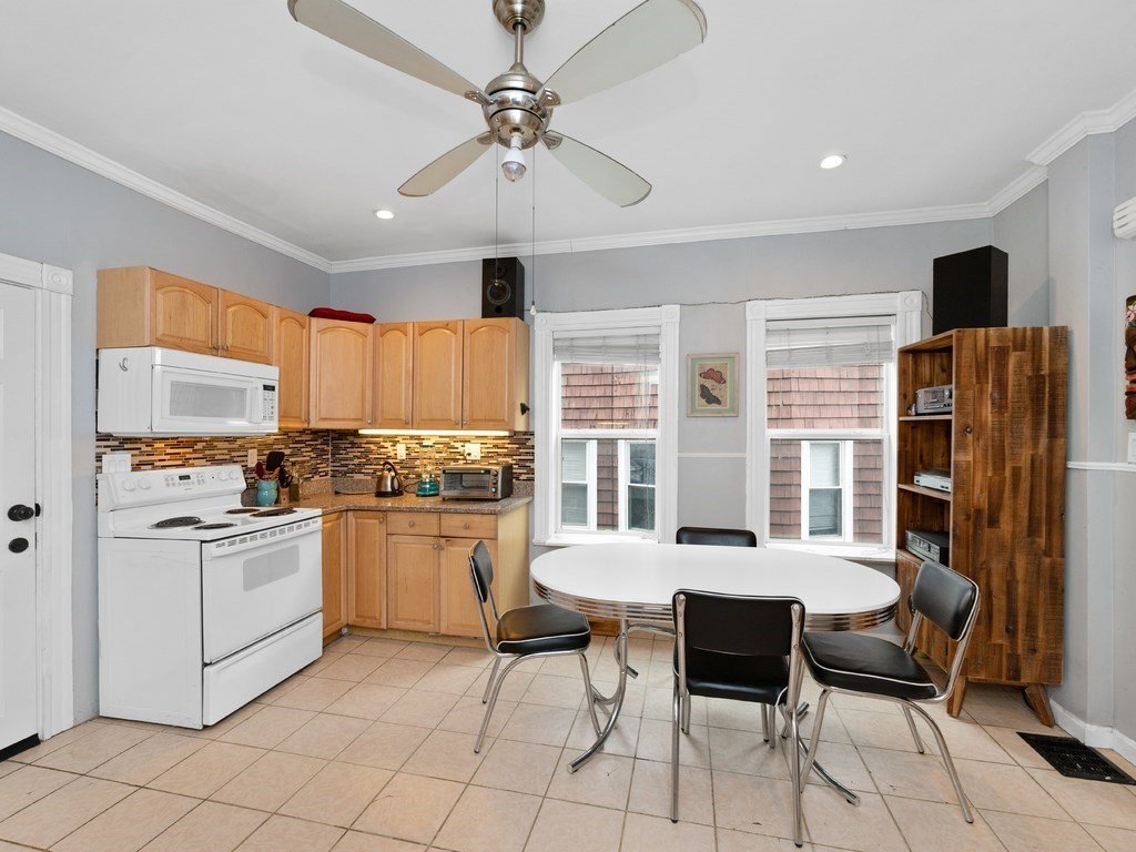 10 Edith Avenue, Unit 1 Everett, MA 02149 - Photo 5 of 12 a kitchen with stainless steel appliances granite countertop a stove a refrigerator a sink a dining table and chairs with wooden floor