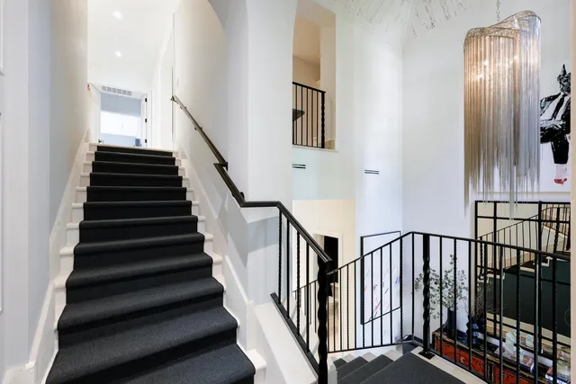 a view of staircase with lots of frames on wall and windows