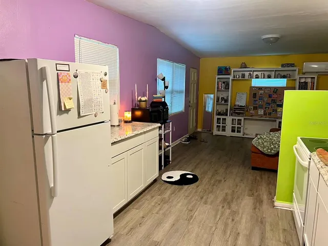 a kitchen with a refrigerator a stove and a dining table with wooden floor