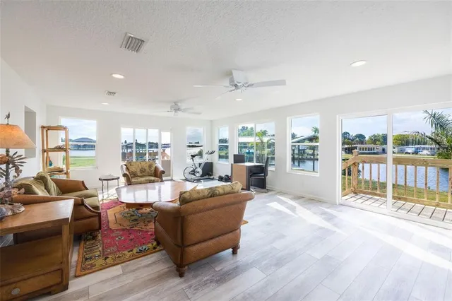 a living room with furniture large windows and wooden floor