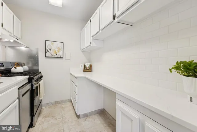 a kitchen with stainless steel appliances a stove and white cabinets
