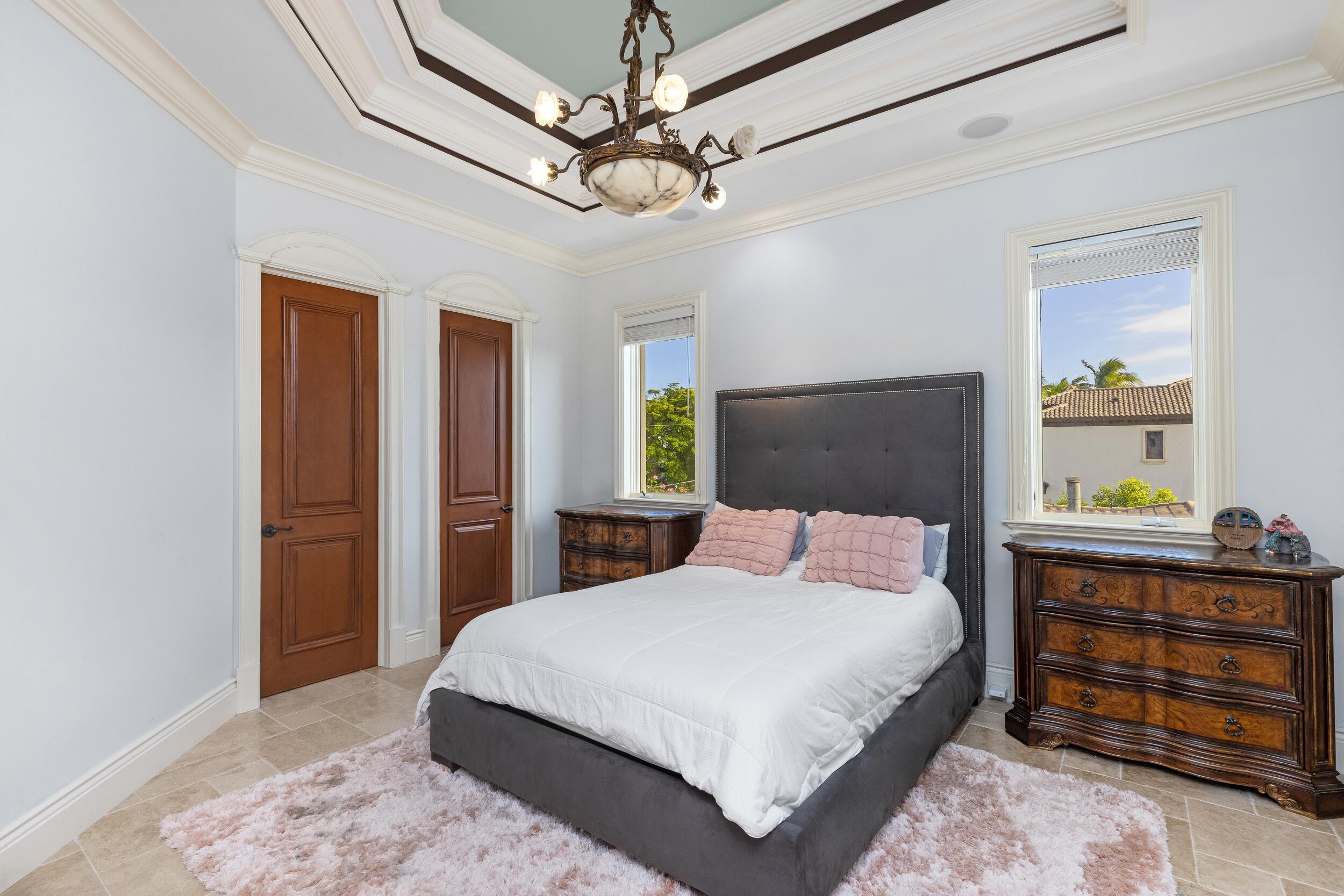 3201 Northeast 27th Avenue Lighthouse Point, FL 33064 - Photo 46 of 66 a bedroom with a bed a dresser and a chandelier