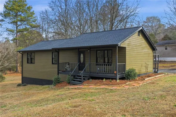 a view of house with backyard and trees in the background
