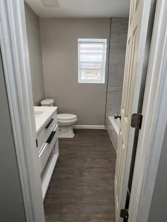 a bathroom with a sink a toilet a shower and a window