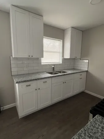 a kitchen with granite countertop a sink a window and cabinets