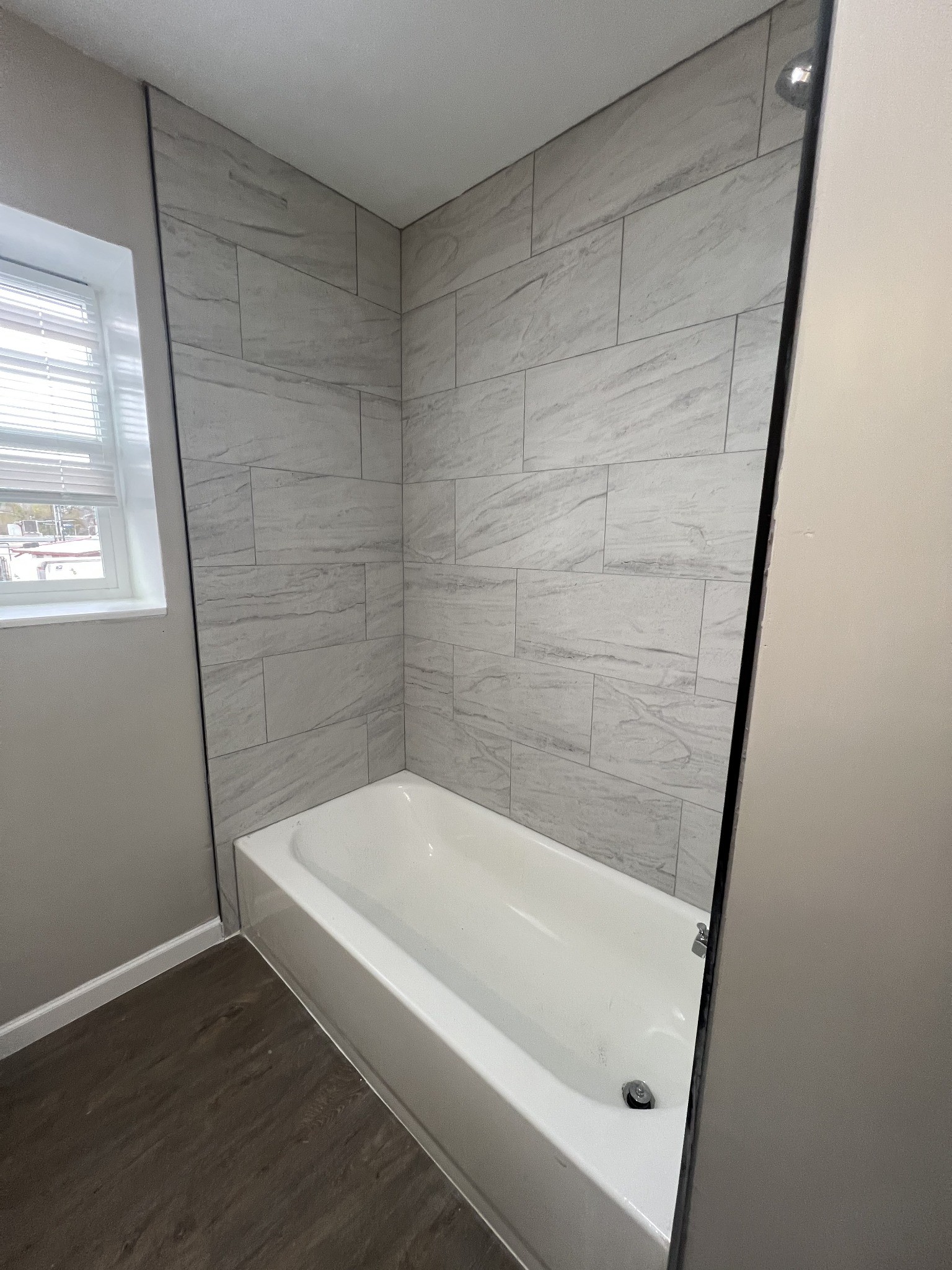 9745 Long Point Road, Unit 37 Houston, TX 77055 - Photo 3 of 17 Bathtub with marble-look tile surround and window for natural light.