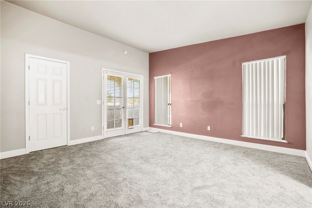 3311 Sunfish Drive, Unit D Henderson, NV 89014 - Photo 13 of 21 A spacious room features a rich, deep red accent wall and neutral carpeting, offering a canvas for personalized design.