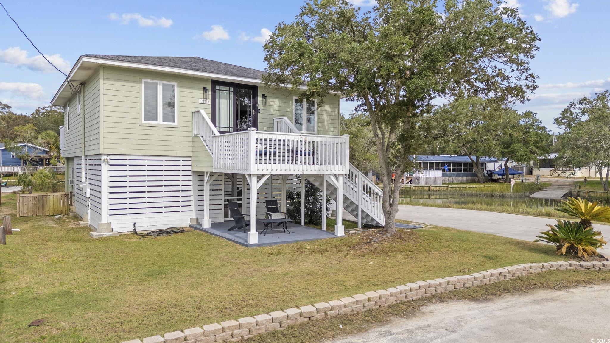 3184 State Rd S-26-816 Murrells Inlet, SC 29576 - Photo 1 of 40 Coastal home featuring a front yard, a wooden deck, and a patio