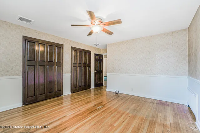 an empty room with wooden floor closet and windows