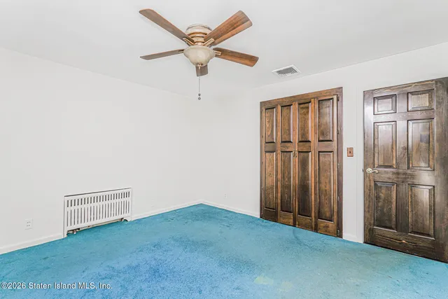 an empty room with closet and a ceiling fan