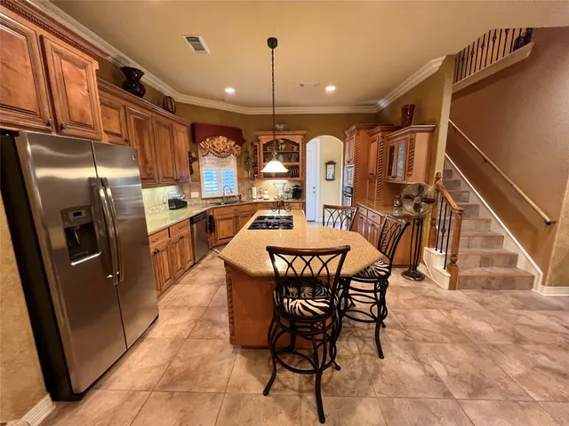 a dining room with stainless steel appliances kitchen island granite countertop a table chairs and a refrigerator