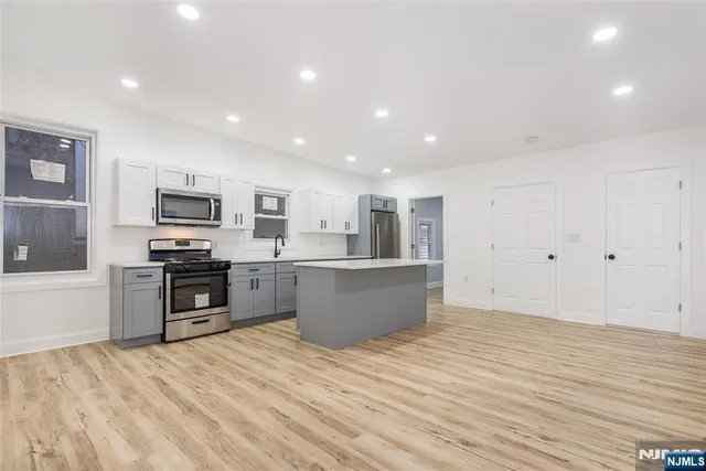 a large kitchen with stainless steel appliances granite countertop a large counter top and wooden floors