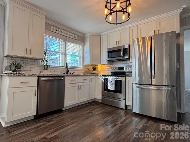 a kitchen with white cabinets stainless steel appliances and window