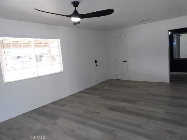 an empty room with wooden floor cabinet and windows