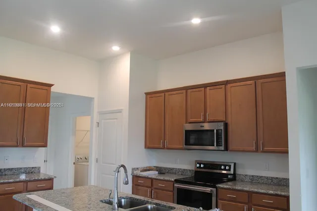 a kitchen with stainless steel appliances granite countertop a stove a microwave a sink and cabinets