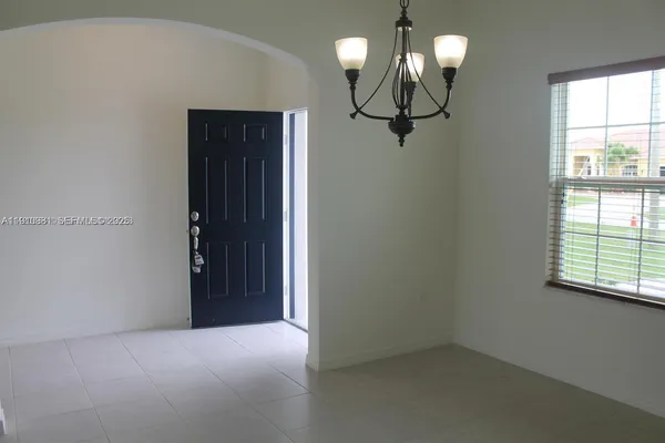 an empty room with chandelier fan and windows