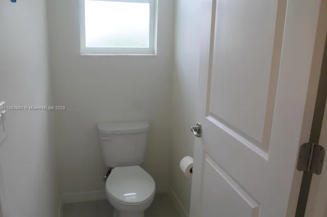 a white toilet sitting in a bathroom next to a window