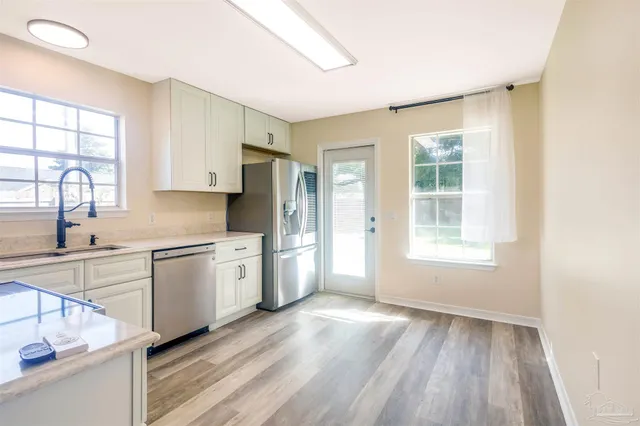 a kitchen with granite countertop wooden floors a sink appliances and cabinets