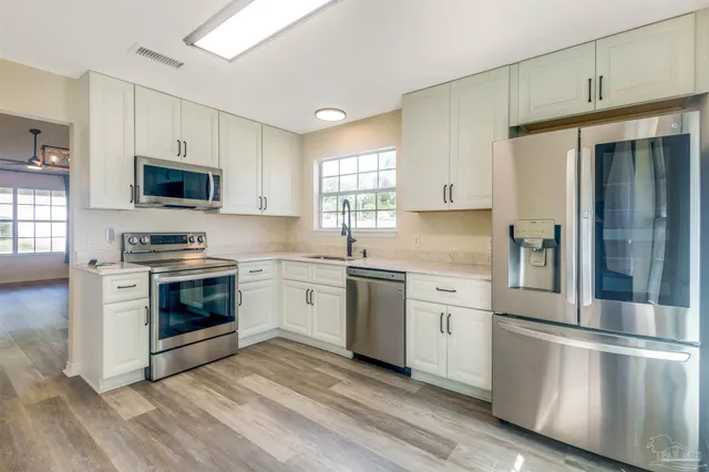 a kitchen with granite countertop white cabinets and stainless steel appliances