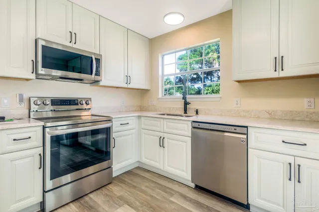 a kitchen with cabinets stainless steel appliances a sink and a window