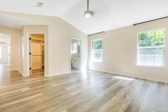 a view of empty room with wooden floor and fan