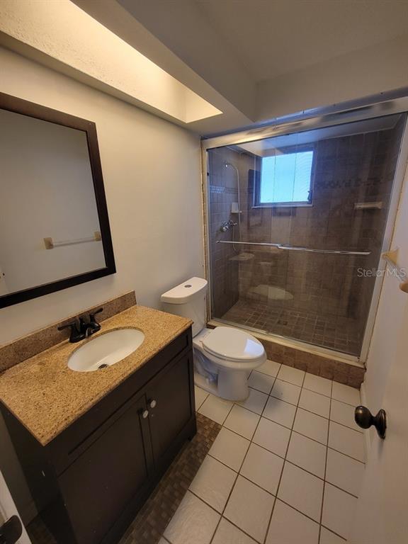 7730 Wicklow Street New Port Richey, FL 34653 - Photo 15 of 19 a bathroom with a granite countertop sink a toilet a mirror and shower