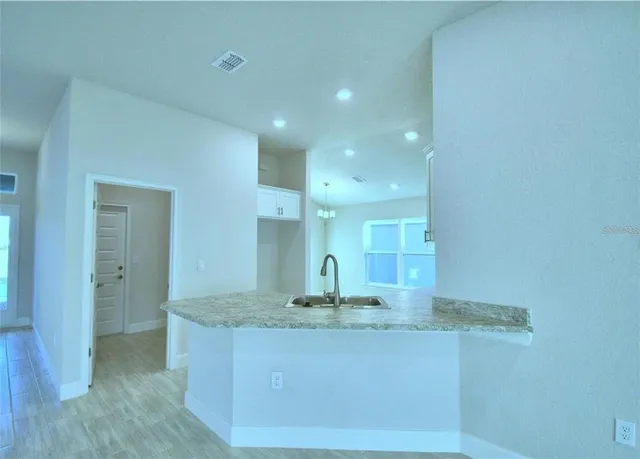 an empty room with wooden floor chandelier and window