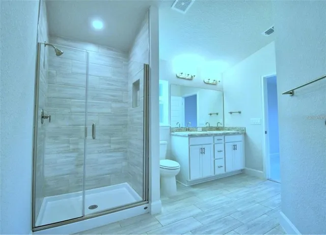 a bathroom with a granite countertop sink a toilet and a shower