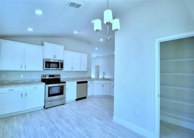 a kitchen with kitchen island granite countertop stainless steel appliances a stove top oven a sink and cabinets