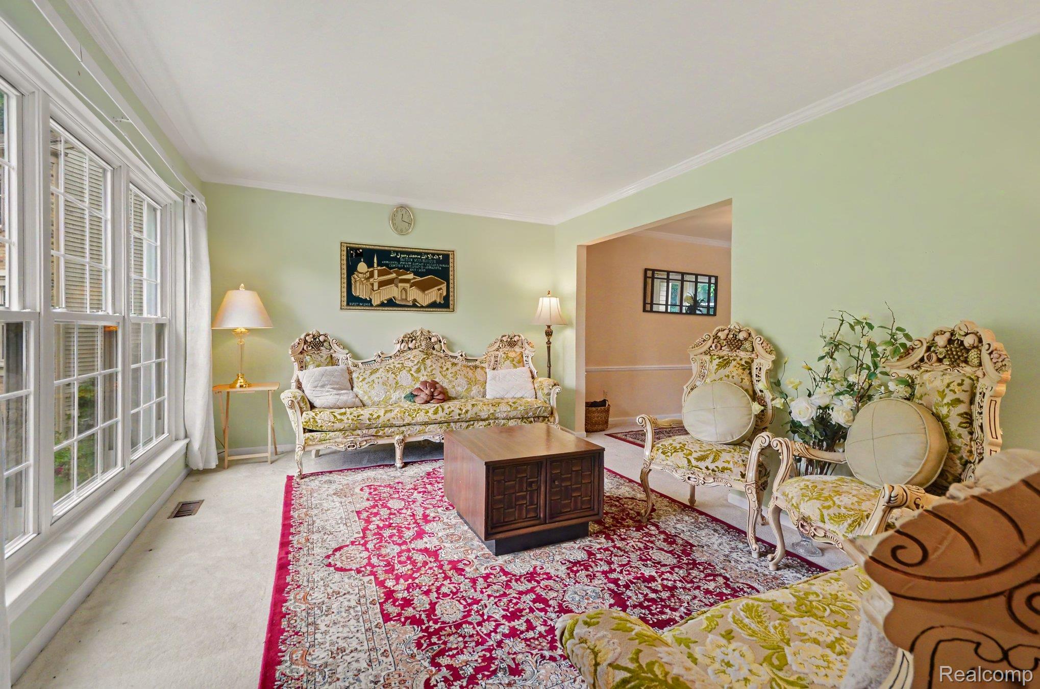 425 Thornridge Court Rochester, MI 48307 - Photo 16 of 35 Bright living space featuring large multi-pane windows, light green wall tones, and white crown molding