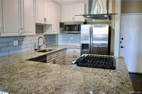a kitchen with kitchen island granite countertop a stove a sink and a refrigerator
