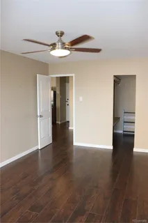 a view of an empty room with wooden floor and a ceiling fan