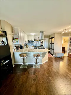 a living room with stainless steel appliances furniture and a wooden floor