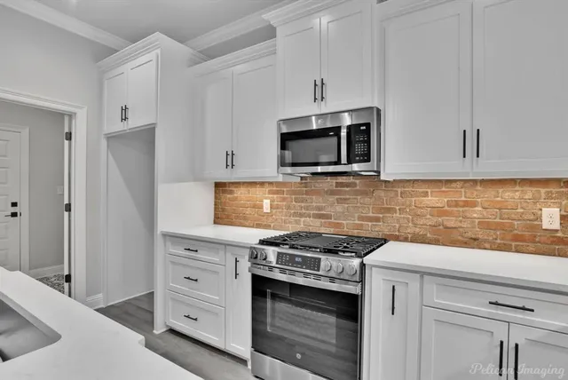 a kitchen with kitchen island granite countertop a sink cabinets and stainless steel appliances